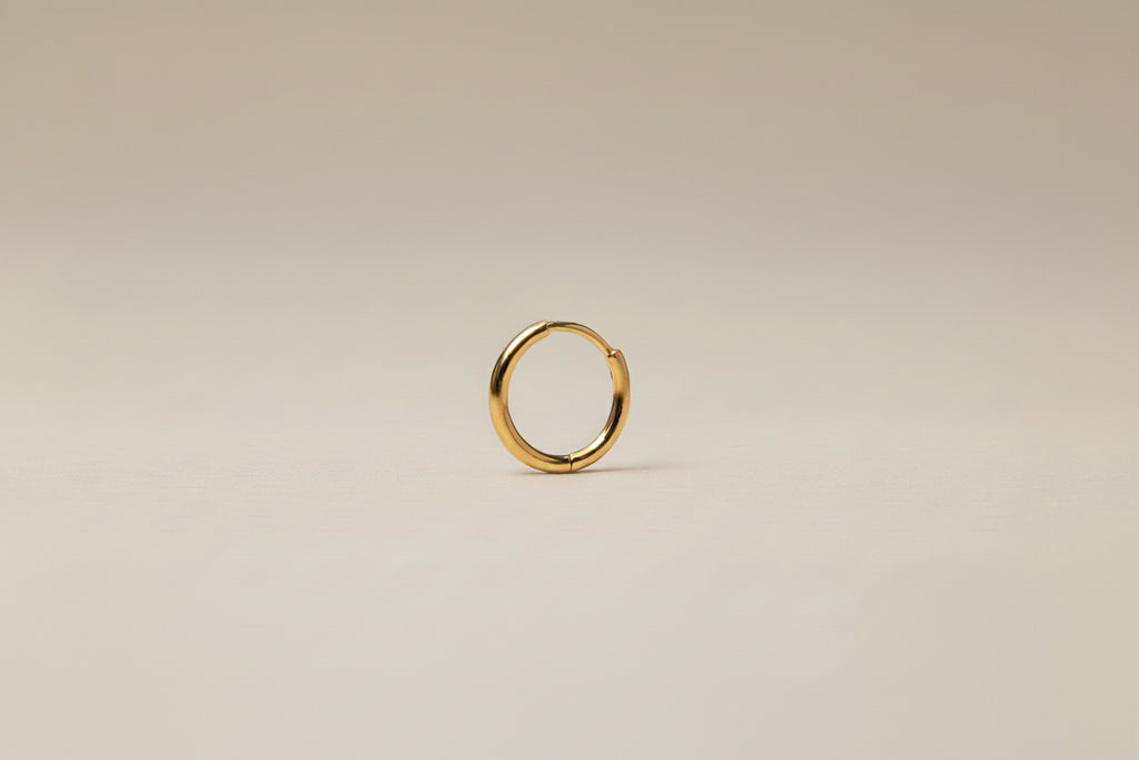 Gold hoop earring on a light gray background