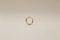Gold hoop earring on a light gray background
